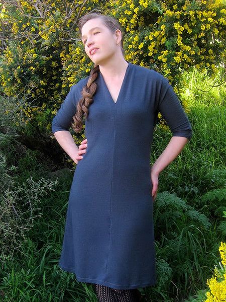 Leimomi, a white woman with her hair in a braid, is shown wearing the Scroop Miramar Dress with 3/4 length sleeves in slate blue wool knit