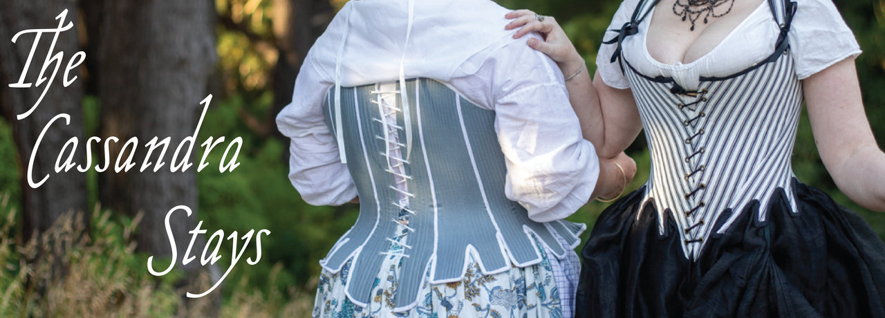 'The Persis Corset' showing a close up of two women's torsos.  The women are wearing corsets: the woman on the left is wearing a light brown corset with light brown bow, and the woman on the right holds a booklet and is wearing a pale pink corset with coral pink bow